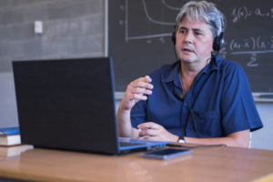 Male Math Professor using laptop to video chat for Online Tuition