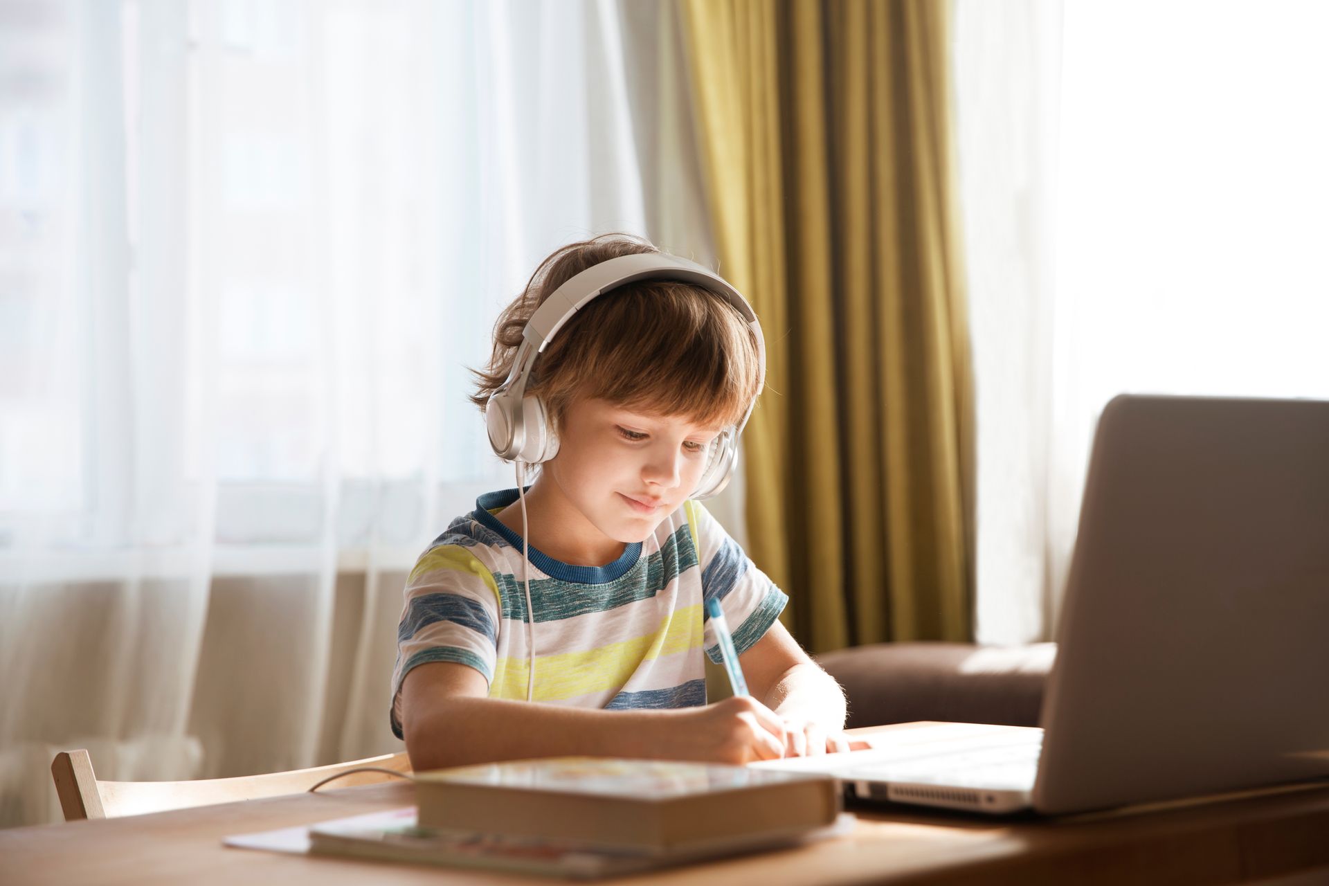 Young Boy With Headphones Receiving Online Tuition