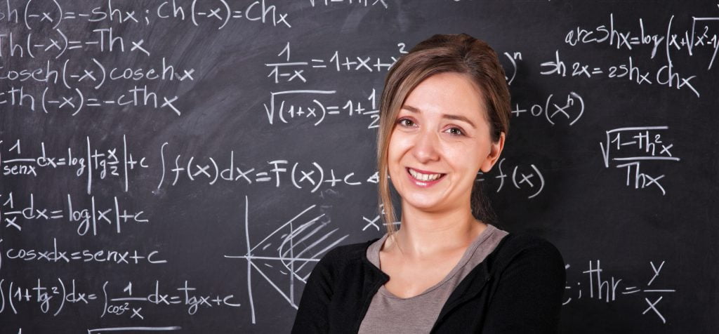 Teacher Standing in Front of Chalk Board full of Maths Equations